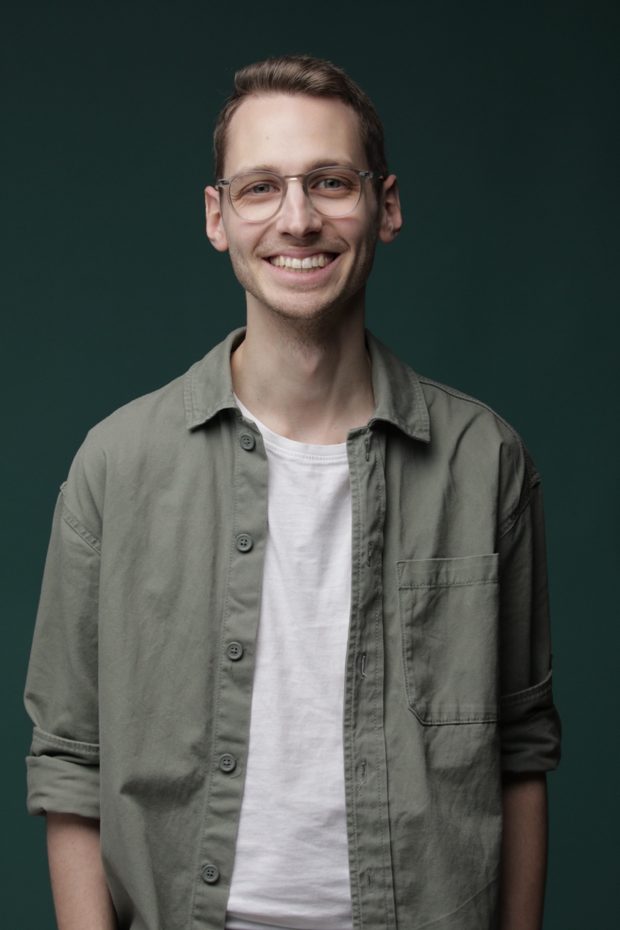 Portraitfoto von Phil Rieger, freundlich in die Kamera blickend, vor neutralem Hintergrund